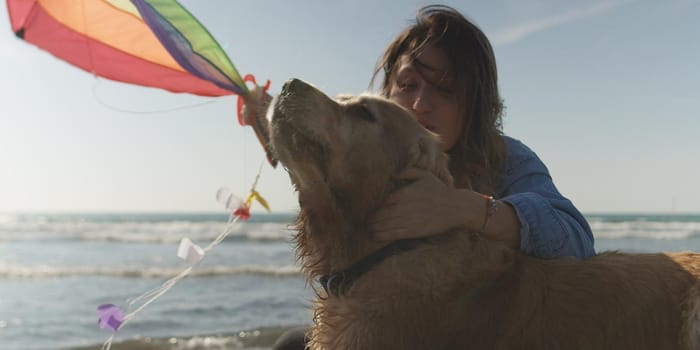 Beautiful Young Woman with dog Holding A Kite at Beach