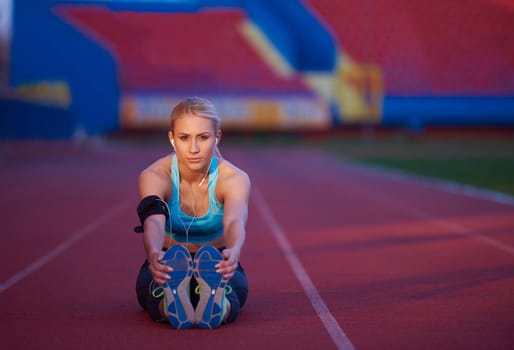 young runner sporty woman relaxing and stretching on athletic race track