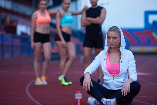 young runner sporty woman relaxing and stretching on athletic race track