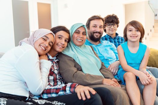 Portrait photo of an Arab Muslim family sitting on a couch in the living room of a large modern house. Selective focus. High quality photo