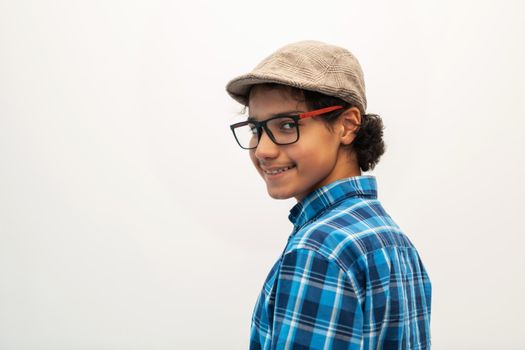 portrait of smart-looking Arab teenager with glasses wearing a hat in casual school look isolated on white copy space. High quality photo