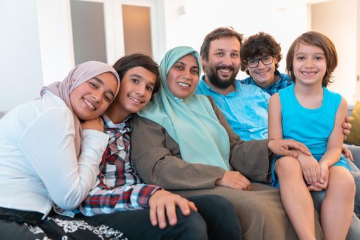 Portrait photo of an Arab Muslim family sitting on a couch in the living room of a large modern house. Selective focus. High quality photo