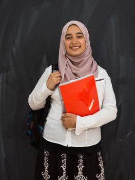 portrait of a happy female middle eastern university student against a black chalkboard in a classroom. High quality photo