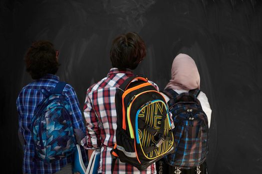 Arabic teenagers, students group  portrait against black chalkboard wearing backpack and books in school