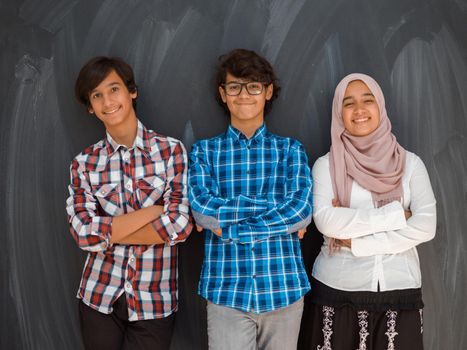 A portrait of a group of Arab teenagers with crossed arms standing in front of a school board. The concept of modern and successful education. High quality photo