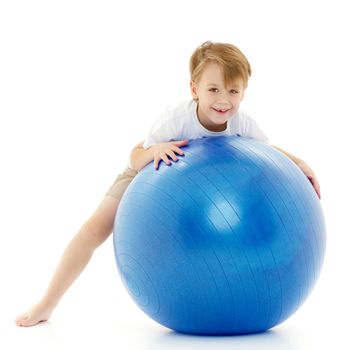 Cute little boy on the big ball is engaged in fitness. On it is a pure white T-shirt on which you can make a picture or write text. The concept of sports, advertising. Isolated on white background.
