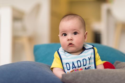 childhood, babyhood and people concept   happy little baby boy sitting between the pillows on sofa at home