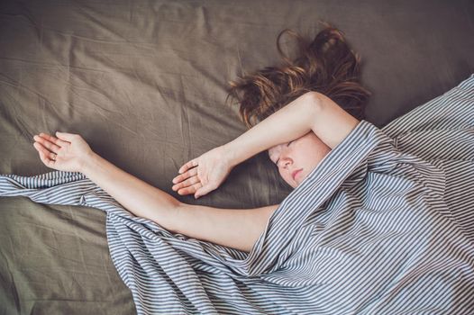 Beautiful young woman lying down in bed and sleeping, top view. Do not get enough sleep concept.