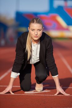 business woman in start position ready to run and sprint on athletics racing track