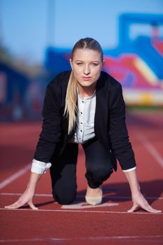 business woman in start position ready to run and sprint on athletics racing track