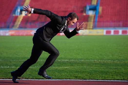 business man in start position ready to run and sprint on athletics racing track