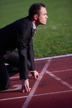 business man in start position ready to run and sprint on athletics racing track