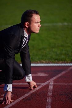 business man in start position ready to run and sprint on athletics racing track