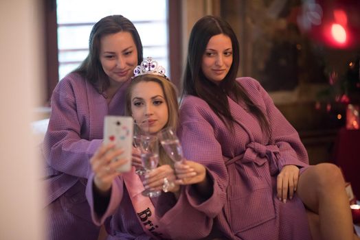 three young beautiful happy girls doing Selfy on bachelorette party at a luxury spa with champagne