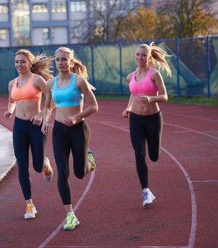 athlete woman group  running on athletics race track on soccer stadium and representing competition and leadership concept in sport