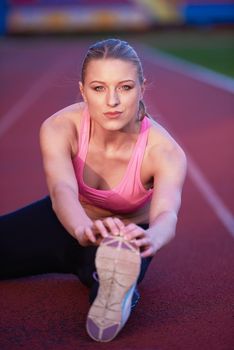 young runner sporty woman relaxing and stretching on athletic race track