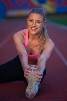 young runner sporty woman relaxing and stretching on athletic race track