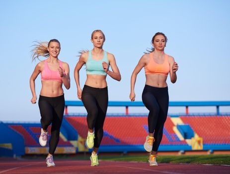 athlete woman group  running on athletics race track on soccer stadium and representing competition and leadership concept in sport