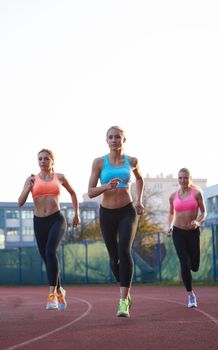 athlete woman group  running on athletics race track on soccer stadium and representing competition and leadership concept in sport