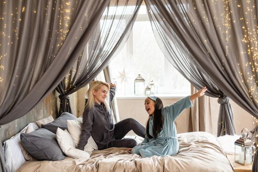 Woman and young girl lying in bed smiling.