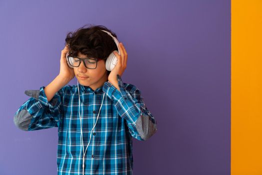 Teenage Boy Wearing Headphones And Listening To Music purple background. High quality photo