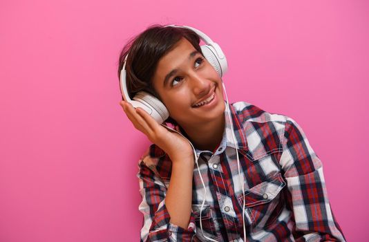 Arabic Teenage Boy Wearing Headphones And Listening To Music pink background. High quality photo