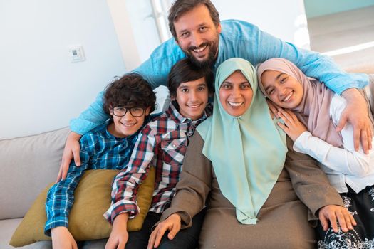 Portrait photo of an Arab Muslim family sitting on a couch in the living room of a large modern house. Selective focus. High quality photo