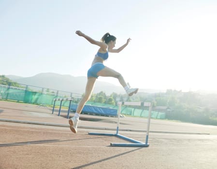 beautiful young woman exercise jogging and runing on athletic track on stadium at sunrise