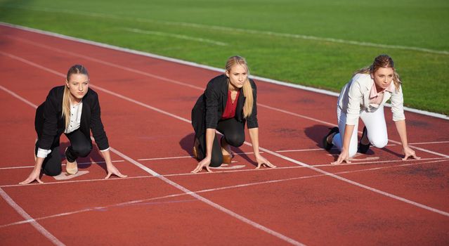 business woman in start position ready to run and sprint on athletics racing track