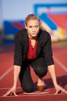 business woman in start position ready to run and sprint on athletics racing track