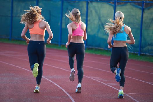 athlete woman group  running on athletics race track on soccer stadium and representing competition and leadership concept in sport