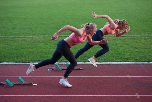 athlete woman group  running on athletics race track on soccer stadium and representing competition and leadership concept in sport