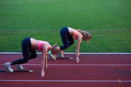 athlete woman group  running on athletics race track on soccer stadium and representing competition and leadership concept in sport