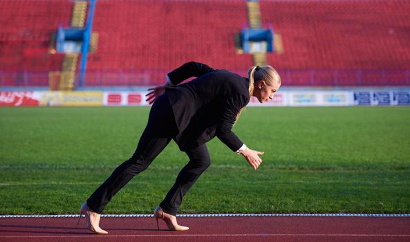 business woman in start position ready to run and sprint on athletics racing track