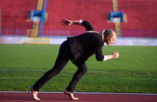 business woman in start position ready to run and sprint on athletics racing track