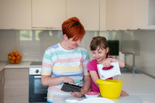 little girl and mom making tastz cake in kithen, family having fun at home 