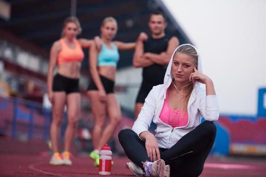 young runner sporty woman relaxing and stretching on athletic race track