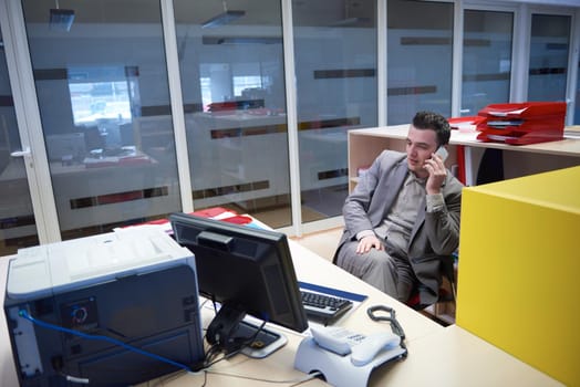 young business man working on computer and talking by phone on modern office indoors