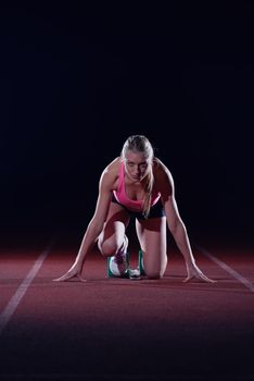 woman  sprinter leaving starting blocks on the athletic  track. Side view. exploding start