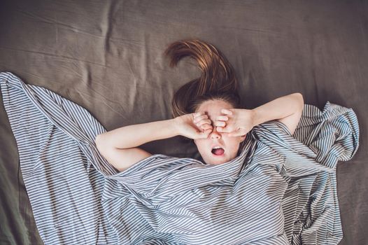 Beautiful young woman lying down in bed and sleeping, top view. Do not get enough sleep concept.