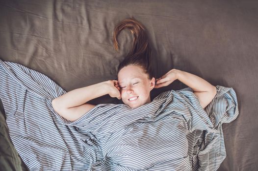 Beautiful young woman lying down in bed and sleeping, top view. Do not get enough sleep concept.