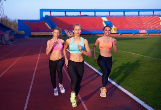 athlete woman group  running on athletics race track on soccer stadium and representing competition and leadership concept in sport