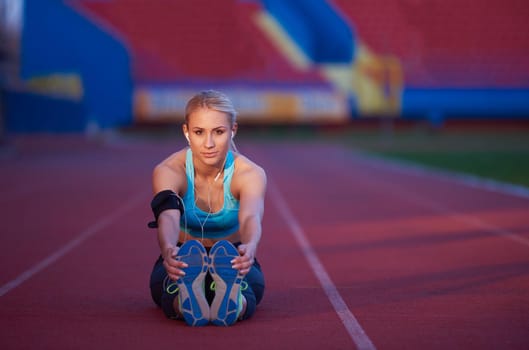 young runner sporty woman relaxing and stretching on athletic race track