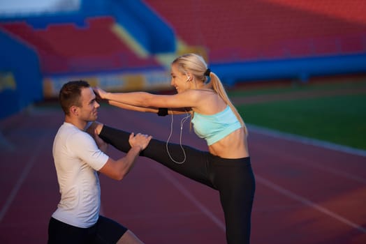 young runner sporty woman relaxing and stretching on athletic race track