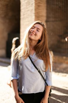 Young pretty female tourist standing in brick wall background. Concept of tourism and youth.