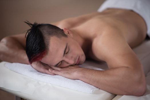 attractive handsome man resting in a spa massage center, lying on table relaxing closed eyes  concept of men beauty health care