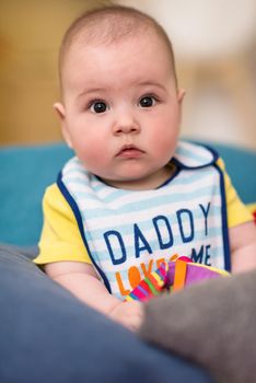 childhood, babyhood and people concept   happy little baby boy sitting between the pillows on sofa at home