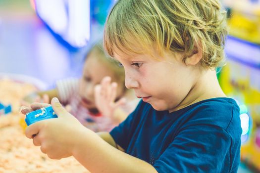 Boy playing with kinetic sand in preschool. The development of fine motor concept. Creativity Game concept.