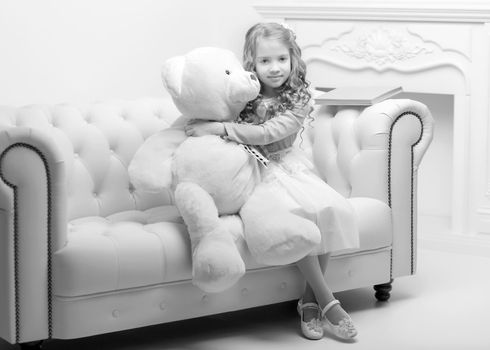 Beautiful little girl with a teddy bear, studio black and white photo. Concept of happy children, style and fashion.