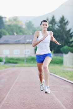 beautiful young woman exercise jogging and runing on athletic track on stadium at sunrise